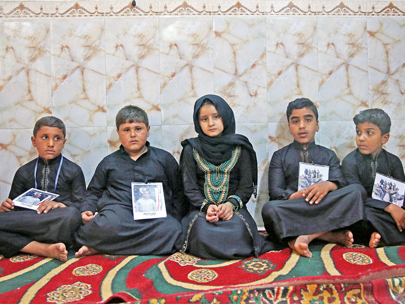 أطفال عراقيون يحملون صورة آبائهم الذين قتلوا على يد «داعش» في حادث حصل في يوليو الماضي بكربلاء (رويترز)