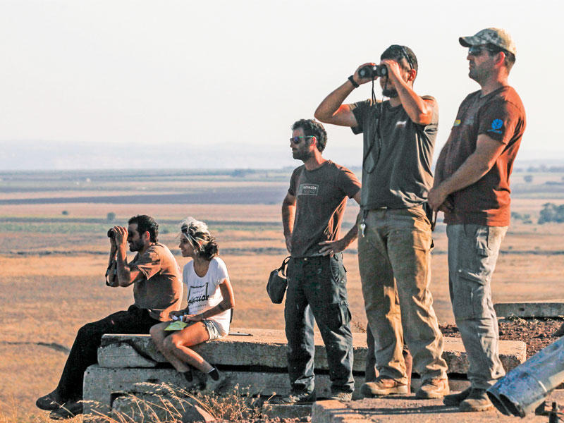 إسرائيليون يشاهدون المعارك السورية من الجانب الذي تحتله إسرائيل في هضبة الجولان      (أ ف ب )