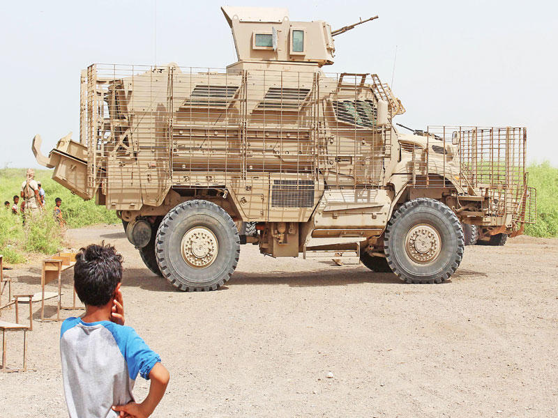 فتى يمني ينظر إلى آلية تابعة للجيش الإماراتي جنوب المخا قبل أيام خلال تنظيم حملة لرفع الوعي بالمتفجرات (أ ف ب)