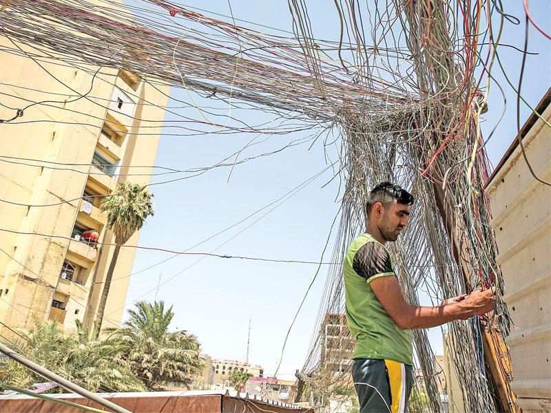 عراقي وسط غابة من الكابلات الكهربائية في بغداد أمس (أ ف ب)n