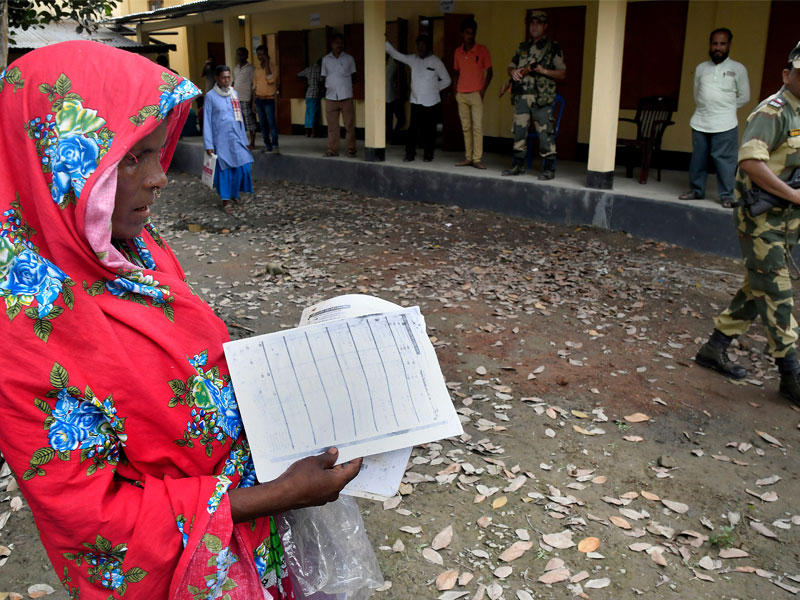 امرأة تتحقق من وثائقها قبل التحقق من اسمها في المسودة الوطنية لمشروع المواطنين
