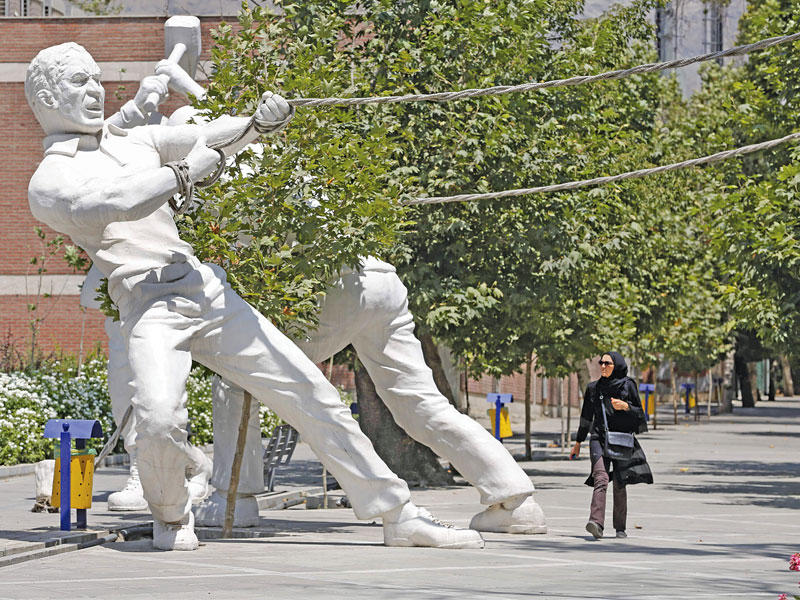 إيرانية تسير بجوار تمثال عملاق أمام حديقة بوسط طهران أمس (أ ف ب)