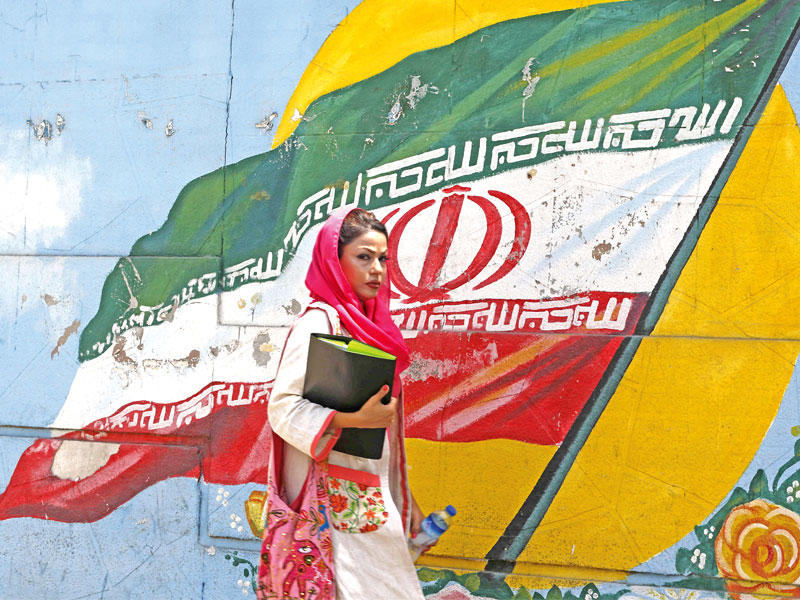 إيرانية تمر أمام جدار رسم عليه العلم الإيراني في طهران أمس  (أ ف ب)