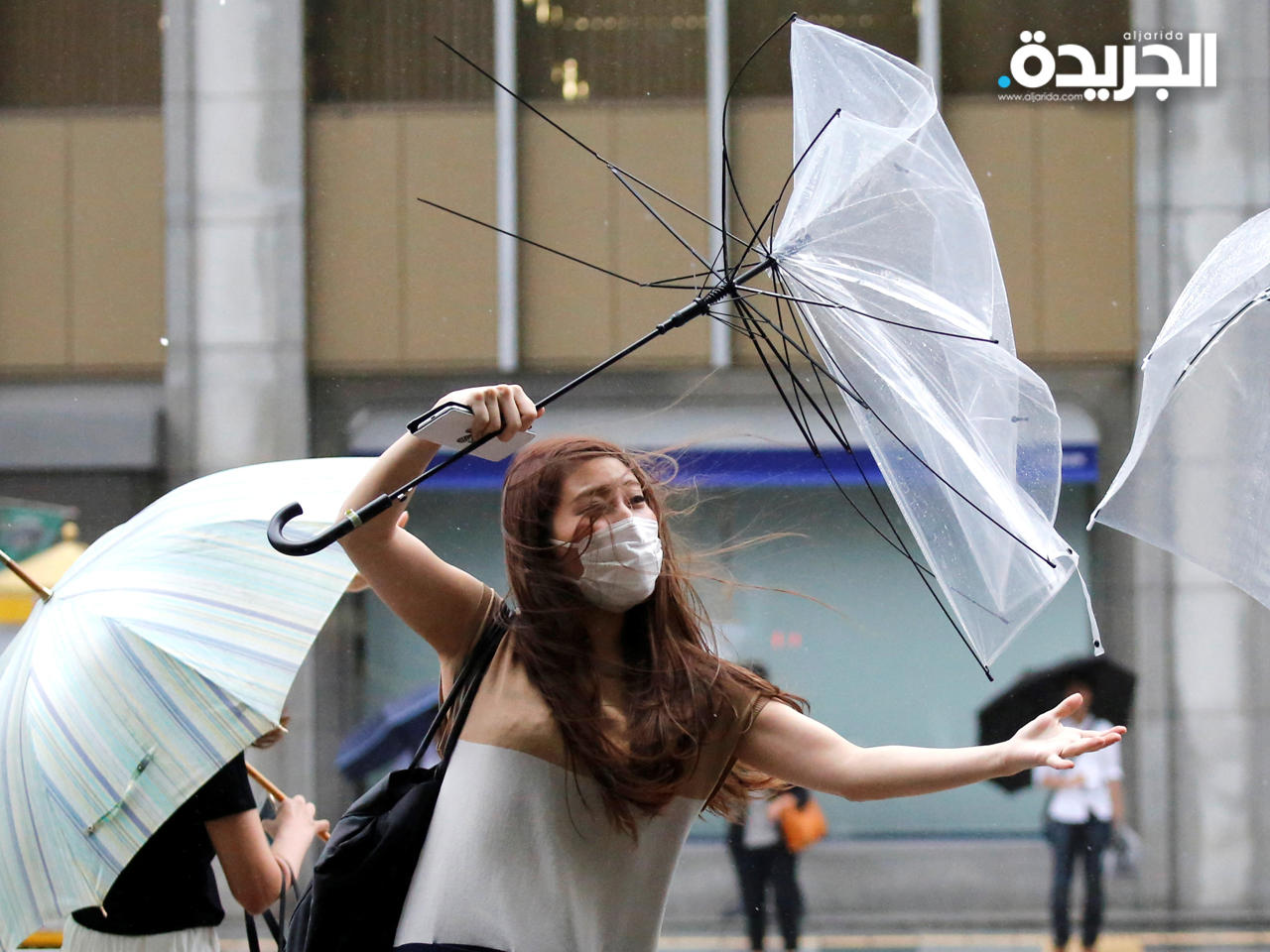 امرأة تفقد السيطرة على مظلة شمسية مع اشتداد الأمطار والرياح في طوكيو