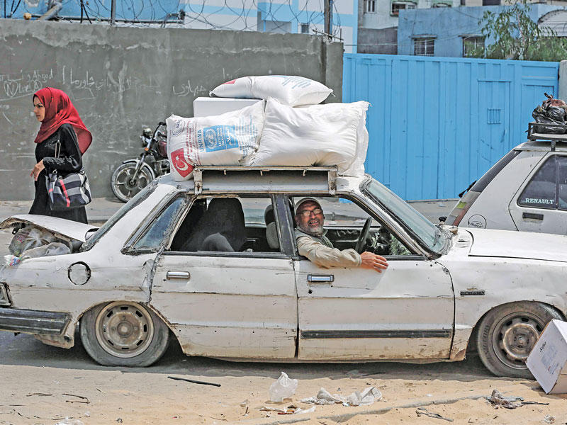 فلسطيني ينقل مواد إغاثية من مركز للأمم المتحدة بجبالية شمال غزة أمس (أ ف ب)