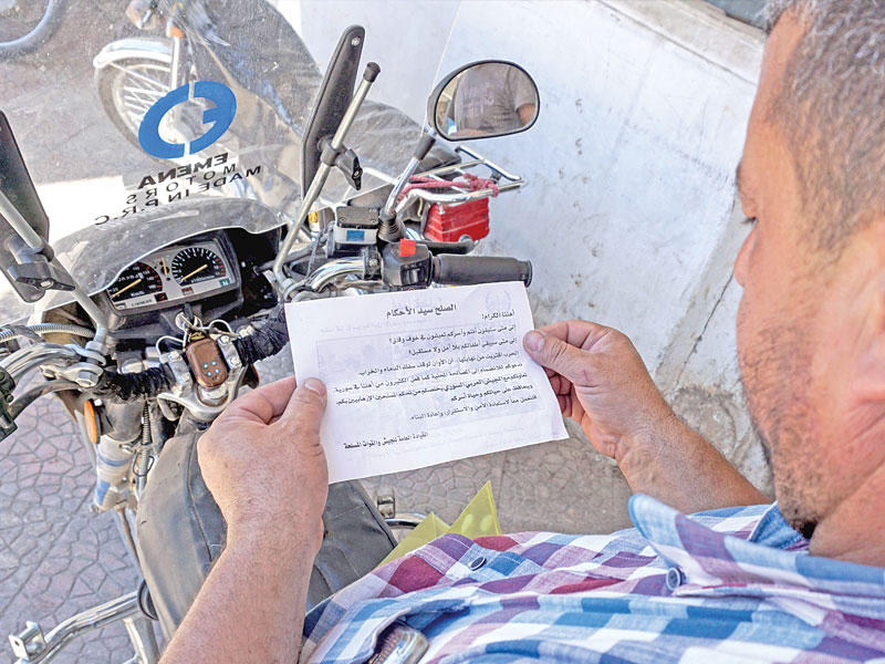 سوري يقرأ منشوراً يدعو للاستسلام ألقته مروحيات النظام على بلدة بنش بإدلب أمس (أ ف ب)n