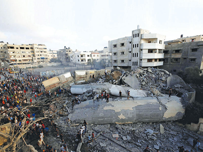 فلسطينيون بمحيط حطام مركز «المسحال» الثقافي عقب استهدافه من الطيران الإسرائيلي في غزة أمس الأول (رويترز)
