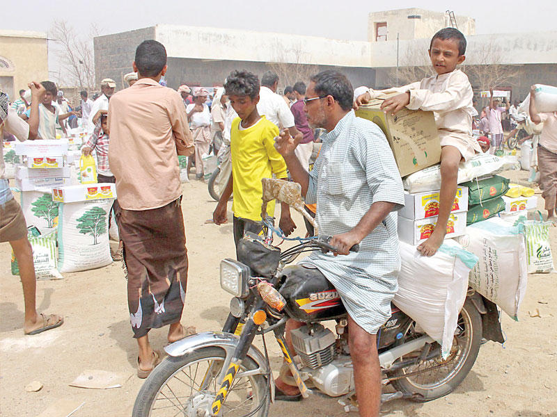 يمني يحمل مع ولده على دراجة نارية مساعدات يابانية في عبس بحجة أمس الأول (أ ف ب)