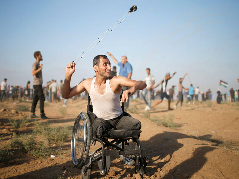  فلسطيني معاق يقذف الإسرائيليين بمقلاعه على حدود غزة أمس (رويترز) 