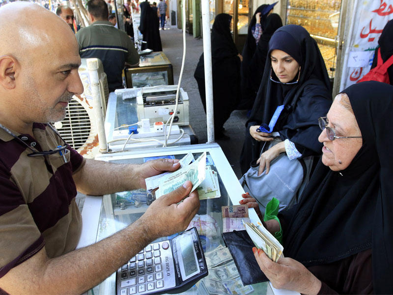إيرانية تغيّر التومان في محل صرافة قرب مرقد الإمام الحسين بكربلاء أمس الأول (إي بي آي)