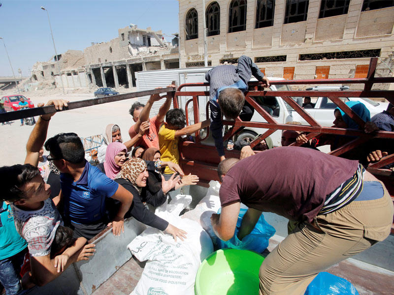عراقيون حول سيارة توزع لحوم الأضاحي بالموصل الأربعاء الماضي  (رويترز)