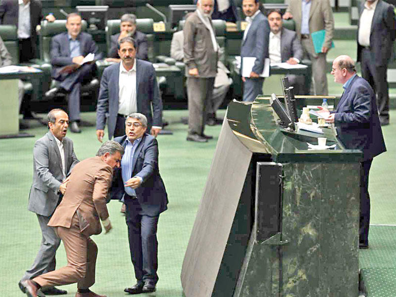 نائبان يمنعان زميلاً من الاعتداء على منصة البرلمان خلال استجواب كرباسيان في طهران أمس (إرنا)