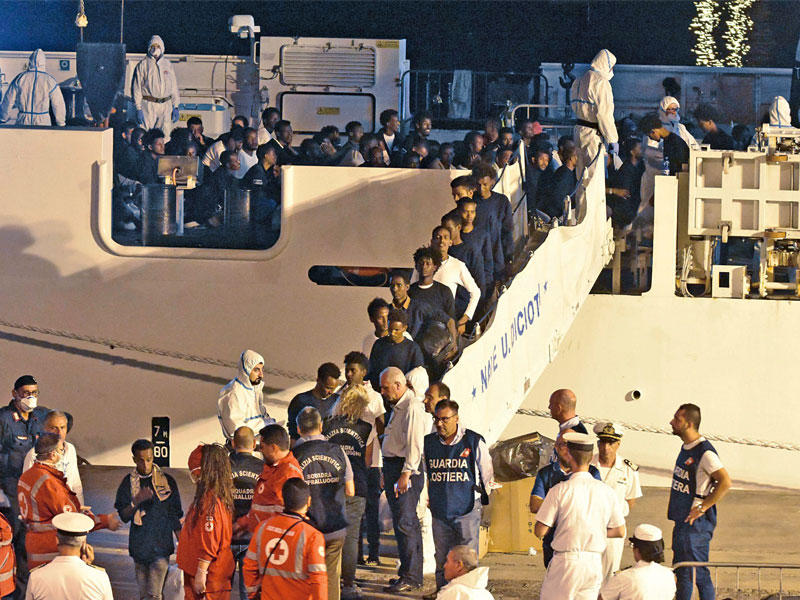  المهاجرون لحظة نزولهم من السفينة «ديتشوتي» في ميناء كاتانيا أمسt (اي بي آي)