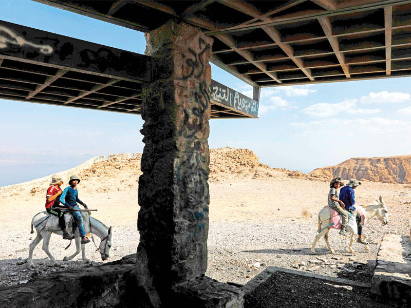 فلسطينيون بدو من قبيلة الرشايدة يتنقلون على الحمير على جبل يطل على البحر الميت أمس الأول (أ ف ب)
