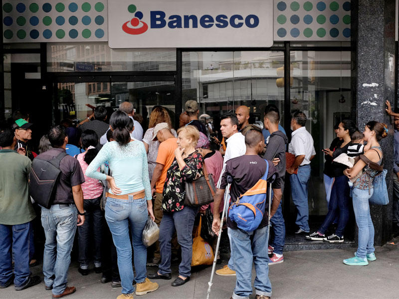 الناس ينتظرون خارج فرع بنك بانيسكو بعد انقطاع التيار الكهربائي في كاراكاس ، فنزويلا