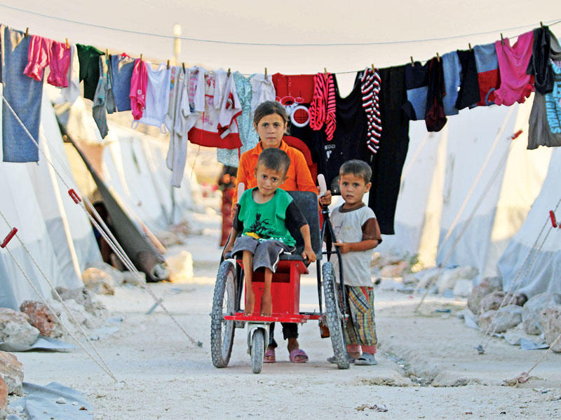 صبية تساعد أخاها المعاق بمخيم شمال إدلب أمس الأول (أ ف ب)n