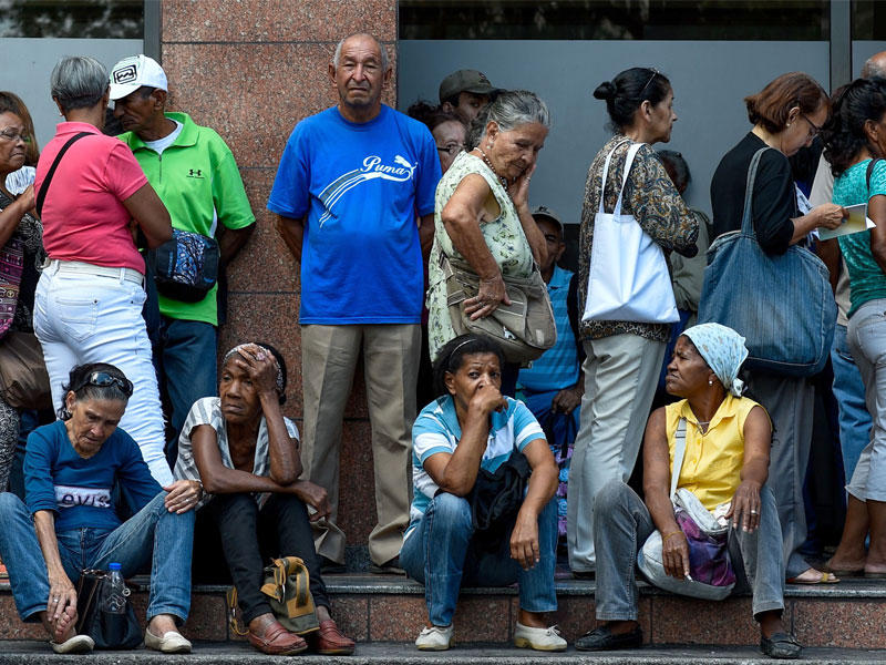 الناس يصطفون لسحب جزء من معاشاتهم التقاعدية خارج فرع البنك ، في كاراكاس