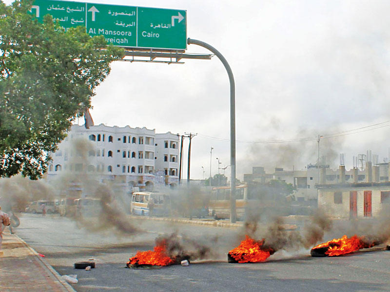 يمني يمر بجوار إطارات مشتعلة أغلقت طريقا بوسط عدن أمس الأول (أ ف ب)