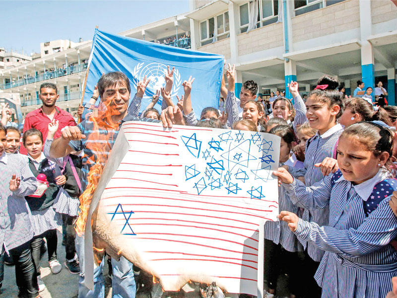 تلاميذ فلسطينيون يحرقون علم الولايات المتحدة في مخيم العروب قرب الخليل أمس (أ ف ب)