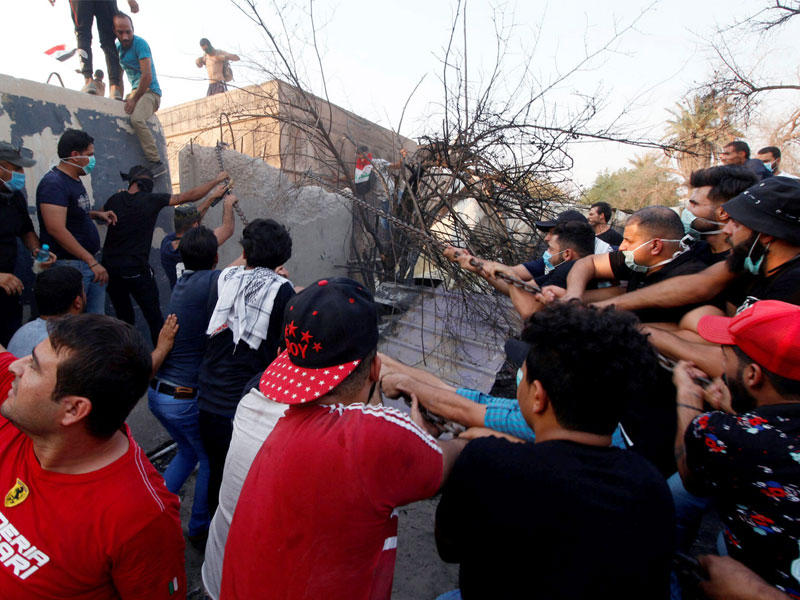 متظاهرون يستكملون هدم سور مقر الحكومة في البصرة أمس (رويترز)