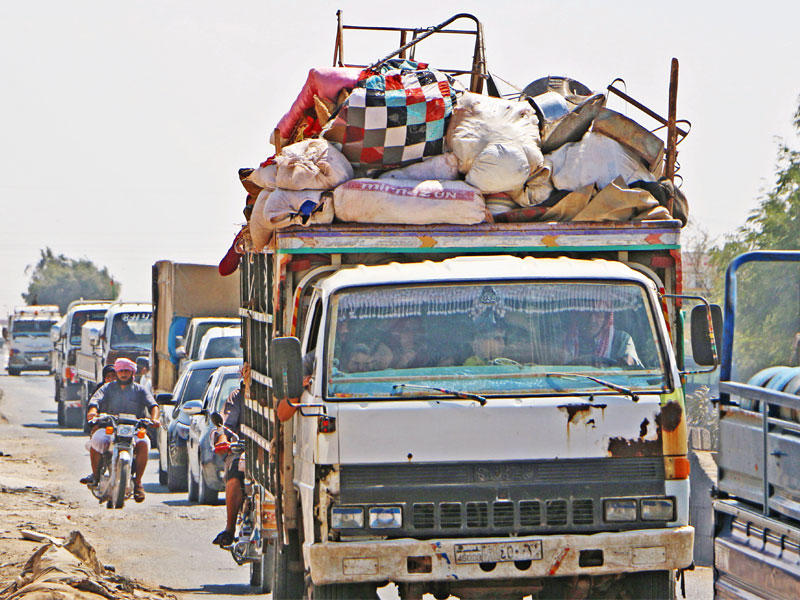 شاحنات محملة بالأمتعة تغادر إدلب أمس (أ ف ب)