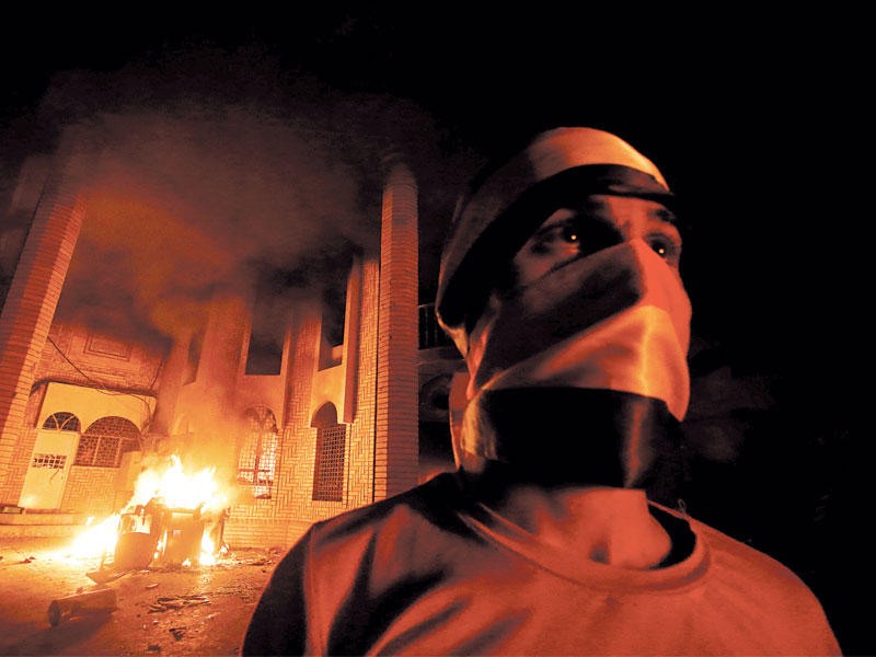 ملثم أمام مقر القنصلية الإيرانية المشتعل في البصرة أمس (رويترز)n