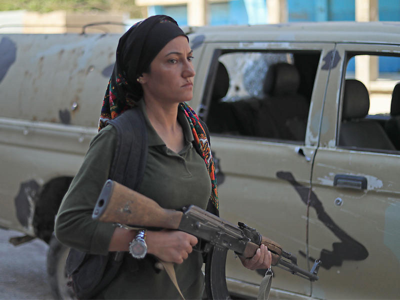 مقاتلة كردية في «الأسايش» بموقع الاشتباك مع قوات النظام في القامشلي أمس (أ ف ب)