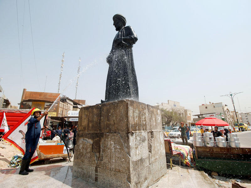 عراقي يغسل أمس تمثالاً للعالم العربي الخليل بن أحمد الفراهيدي في البصرة تعرض لأضرار بسيطة خلال التظاهرات (رويترز)