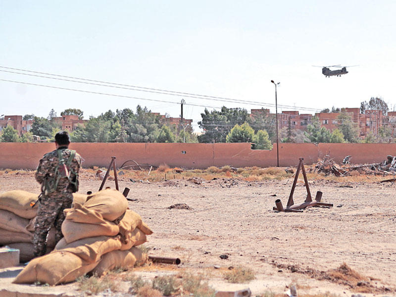 مقاتل كردي يتابع مروحية أميركية في بلدة الشدادي أمس (أ ف ب)