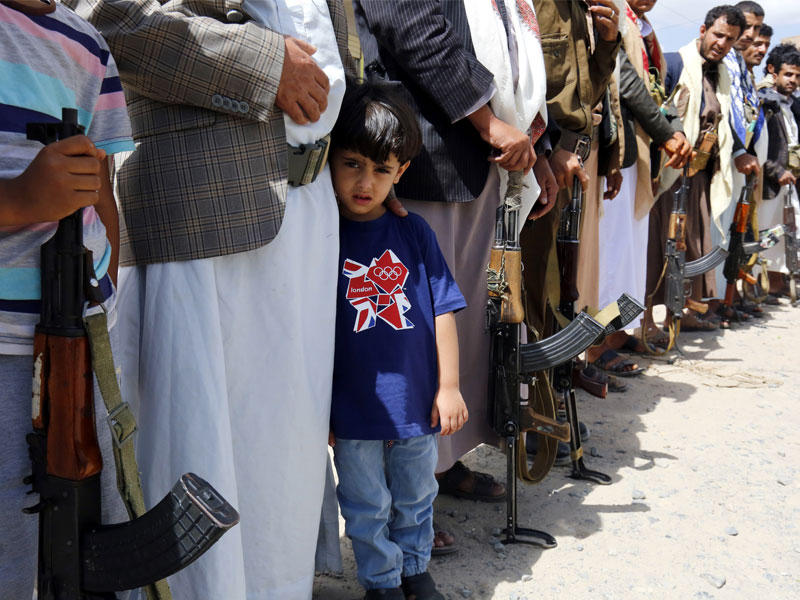 طفل يمني يقف بين الداعمين المسلحين للمتمردين الحوثيين خلال تجمع لحشد المزيد من المقاتلين إلى جبهة القتال في الحديدة