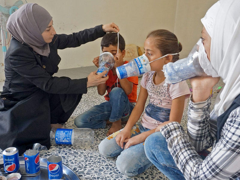 سورية تدرب أسرتها على استخدام قناني فارغة كأقنعة للوقاية من الهجوم الكيماوي المحتمل بمنزلها في بنش أمس (أ ف ب)n