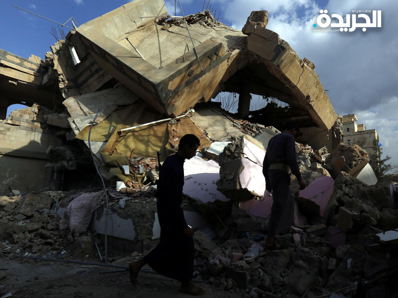 يمنيون يسيرون عبر حطام مبنى مدمر يُزعم أنه تعرض لضربة جوية في صنعاء