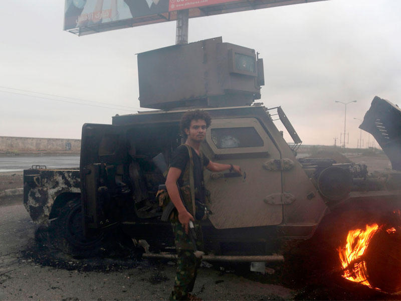 متمردون حوثيون يتفقدون مركبة مدرعة محروقة