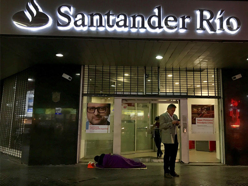 رجل بلا مأوى يقع على بطانية خارج أحد البنوك في الحي المالي في بوينس آيرس ، الأرجنتين