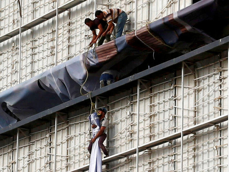 عمال يضعون لافتة إعلانية لمساكن جديدة في القاهرة أمس (رويترز)