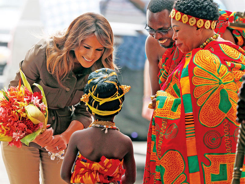 ميلانيا ترامب تتلقى الزهور من طفلة خلال زيارتها كيب كوست في غانا أمس (رويترز)