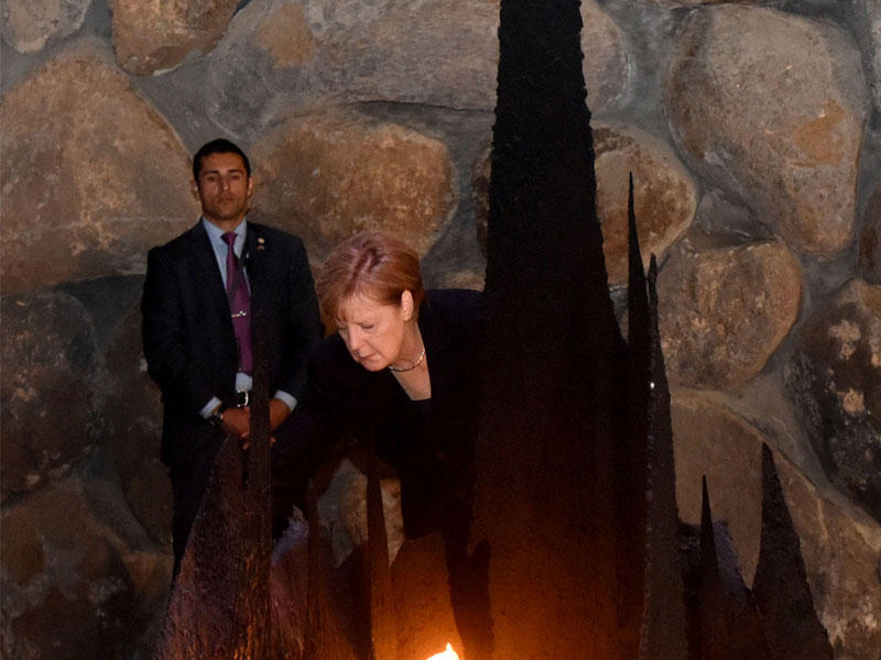 ميركل تضع إكليلاً من الزهور خلال زيارتها نصب المحرقة في القدس امس (رويترز)