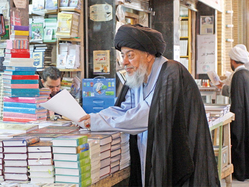 رجل دين شيعي في شارع الحويش المعروف بمكتباته في النجف الأشرف  (أ ف ب)