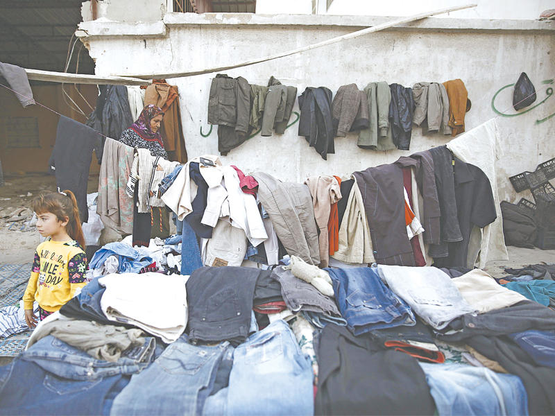 فتاة سورية تبيع الملابس المستعملة في عفرين الثلاثاء الماضي (أ ف ب)