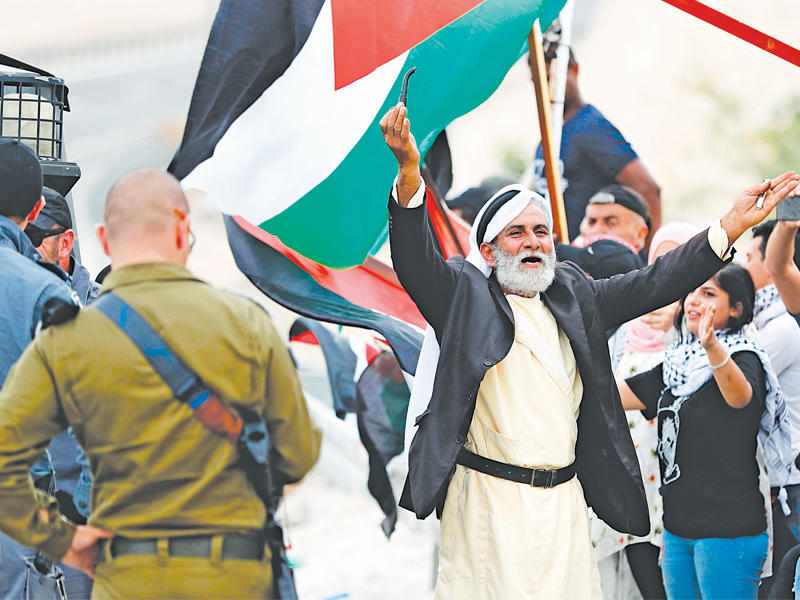 فلسطينيون يتظاهرون قرب نقطة أمنية بمحيط قرية الخان الأحمر التي تعتزم السلطات الإسرائيلية هدمها في الضفة الغربية المحتلة أمس (أ ف ب)