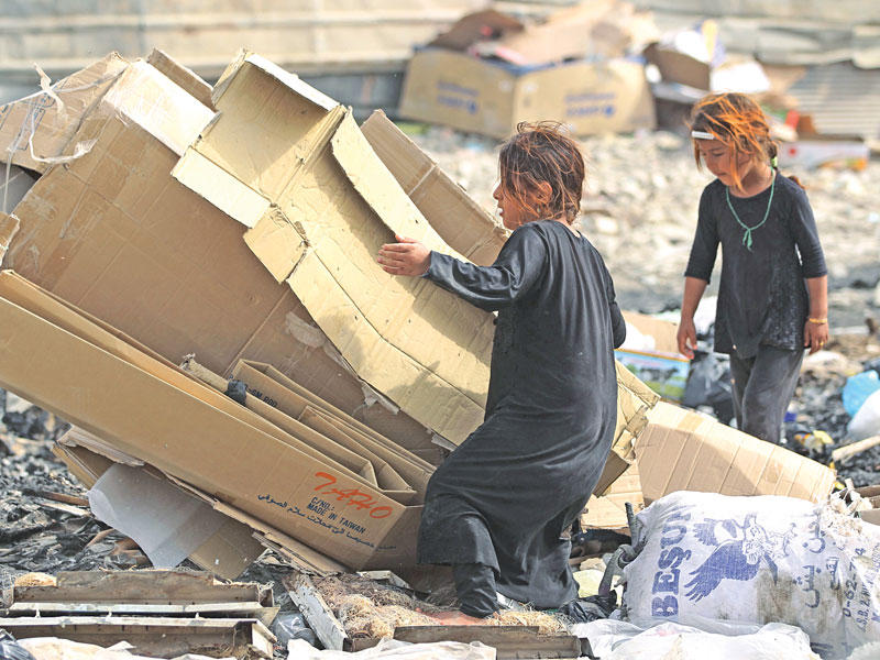 طفلتان تجمعان الكارتون من مكب للنفايات في بغداد الجمعة الماضيةt(أ ف ب)