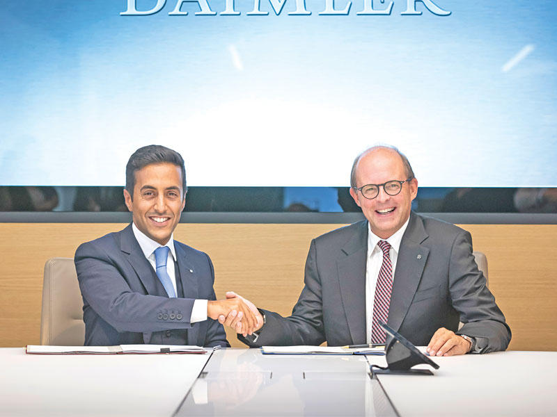 طلال أنور الملا لليسار أثناء توقيع العقد