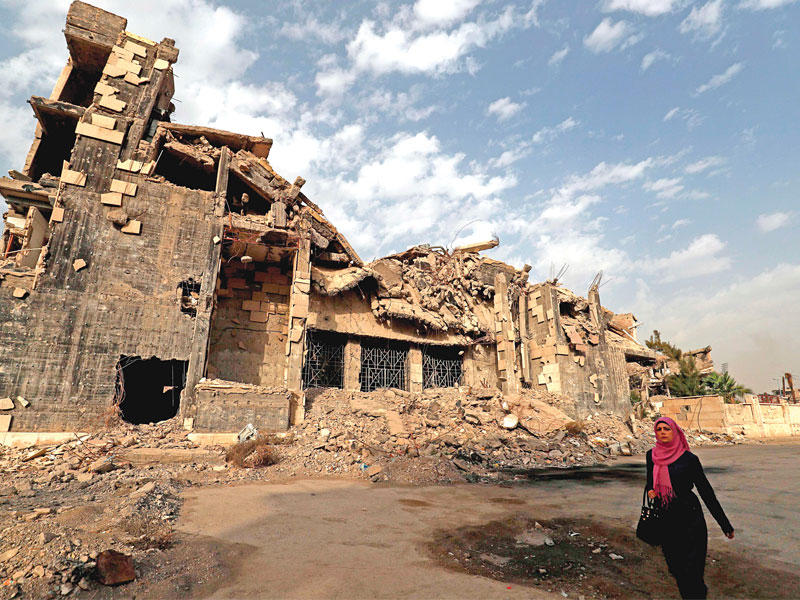 امرأة سورية تمر بين الركام في الرقة قبل أيام (أ ف ب)