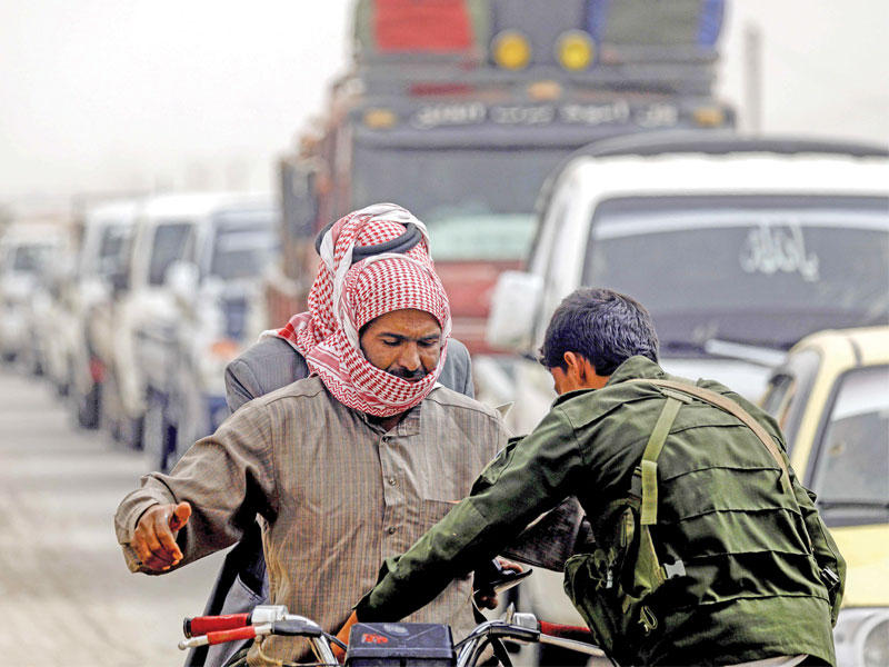 طابور من السيارات التي تنتظر العبور عند نقطة تفتيش تابعة لـ«سورية الديمقراطية» في الرقة الثلاثاء الماضي (أ ف ب)