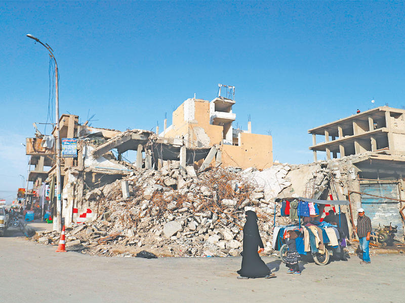 سورية تمر أمام بائع متجول في أحد شوارع الرقة المدمرة أمس الأولt(أ ف ب)