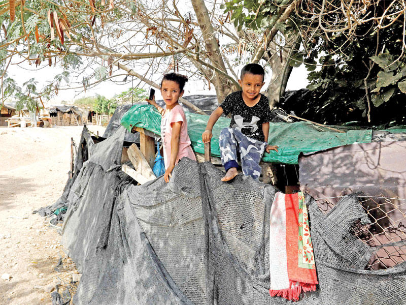 طفلان فلسطينيان يلهوان على سقف كوخهما المكون من الخشب والألواح المعدنية في قرية خان الأحمر أمس         (ا ف ب)