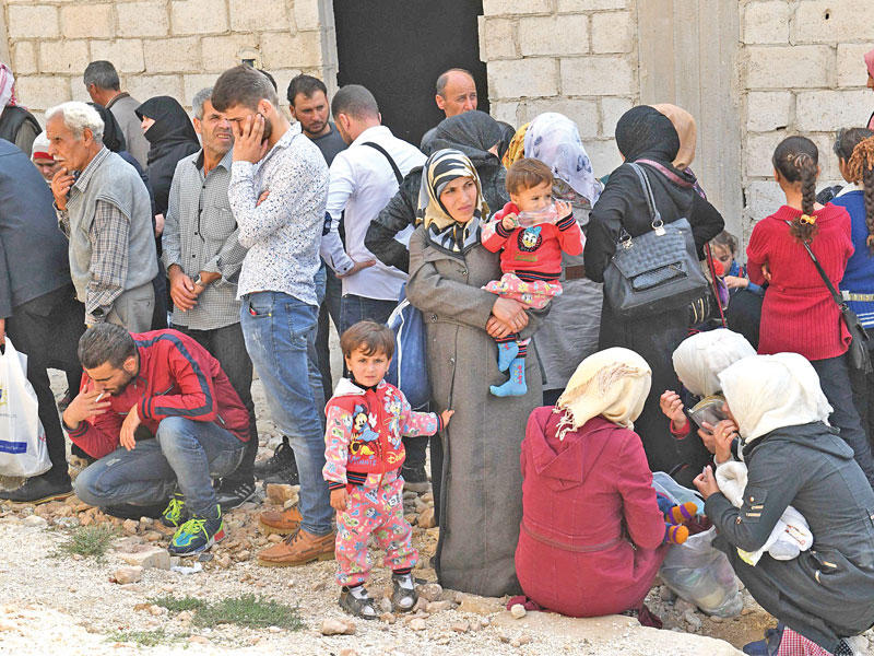 سوريون عند معبر أبوالظهور ينتظرون دورهم للعبور من مناطق المعارضة إلى مناطق النظام في إدلب  (أ ف ب)