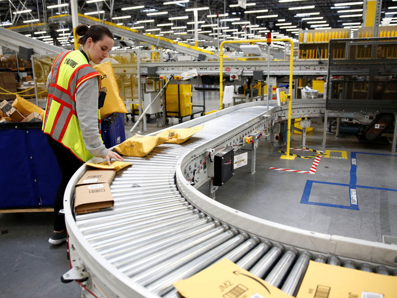 عاملة تفحص طروداً في أحد مراكز أمازون بواشنطن أمس الأول (رويترز)