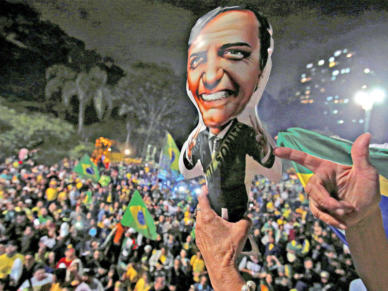 مؤيدو بولسونارو يحتفلون بفوزه حاملين صوره وأعلاماً برازيلية أمس الأول       (رويترز) 