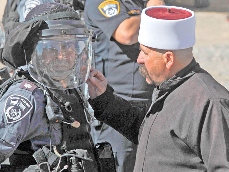 رجل من الموحّدين الدروز يتحدّث مع شرطي إسرائيلي في مجدل شمس أمس        (أ ف ب)